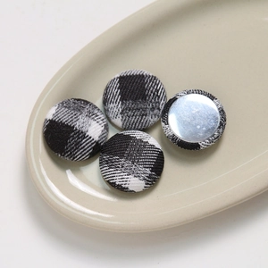 Close-up of black and white checkered fabric buttons with metallic silver backing