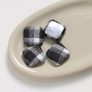 Detail of square black and white checkered fabric buttons with smooth metal backing