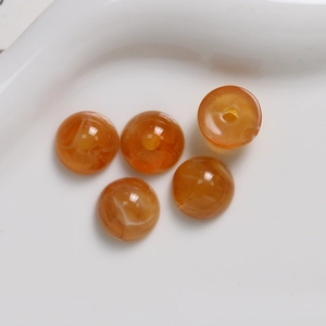 Close-up of 12mm orange resin round beads with white marble texture for DIY jewelry making