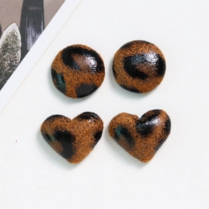 Macro shot of leopard print heart and round fabric buttons for DIY jewelry making
