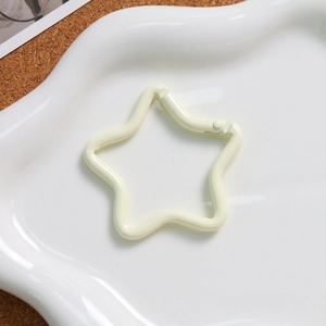 Detailed view of a cream-colored star-shaped spring buckle on a ceramic plate for DIY crafts