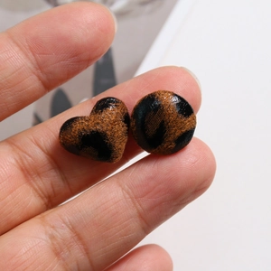 Macro view of leopard print heart and round fabric buttons for DIY jewelry making