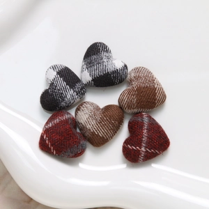 Macro shot of plaid fabric heart charms for DIY crafts on a white tray display