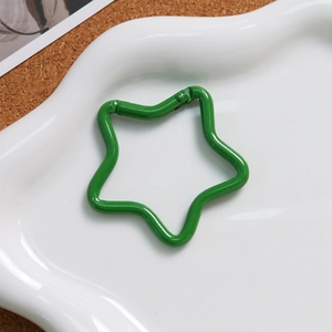 Close-up of a green star-shaped alloy spring clasp on a white plate for DIY crafts