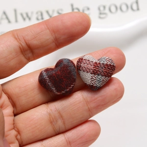 Macro detail of red plaid fabric heart-shaped buttons for DIY jewelry making and crafts