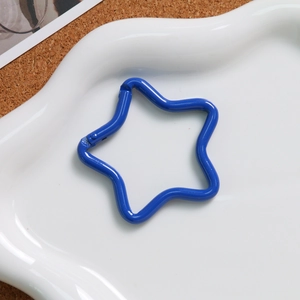 Macro shot of a deep blue star-shaped alloy spring clasp on a white ceramic tray