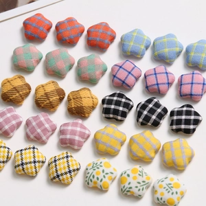 Flat lay of colorful star-shaped fabric buttons with various plaid and floral patterns for DIY