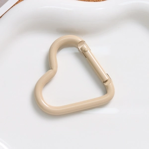 Macro shot of a beige macaron heart-shaped alloy spring clasp on a white plate