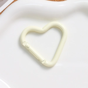 Macro view of cream yellow heart-shaped alloy spring clasp on a white ceramic tray