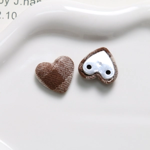 Close-up of heart-shaped brown plaid fabric buttons with metal base for DIY crafts