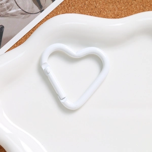 Close-up of a white heart-shaped spring clasp on a ceramic plate for DIY keychains