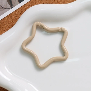 Close-up of cream-colored star-shaped metal spring clasp on a white wavy porcelain plate