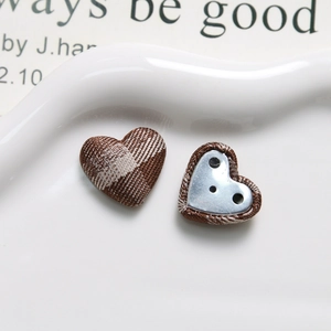 Macro detail of heart-shaped brown plaid fabric buttons with 3-hole metal base for DIY craft