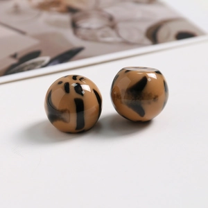 Vue macro de deux perles rondes en résine à motif léopard pour la création de bijoux DIY
