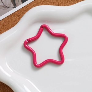 Detail of rose pink star-shaped spring hook clasp in a ceramic dish for DIY projects