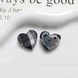 Detail of heart-shaped fabric buttons with black and white plaid pattern and metal back