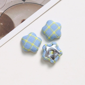 Detailed view of yellow and blue plaid fabric star-shaped buttons with metal bases