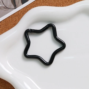 Close-up of black matte star shaped alloy spring clasp on a decorative ceramic tray