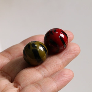 Gros plan de perles en résine avec motif léopard rouge et jaune pour création de bijoux