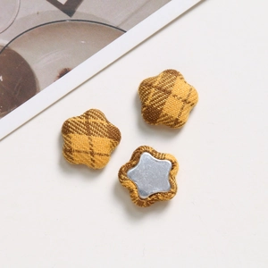 Macro detail of star-shaped plaid fabric buttons with flat metal backing for DIY crafts