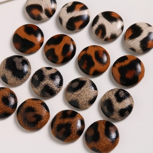 Flat lay of 15 round leopard print fabric buttons for DIY jewelry and hair accessories