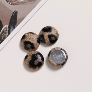 Close-up of leopard print fabric buttons with polished flat metal base for DIY jewelry