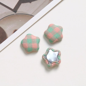 Close-up of star-shaped pink and green plaid fabric buttons with silver metal backings