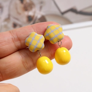 Detailed macro view of yellow and purple plaid fabric star earring with yellow drop bead