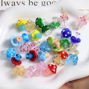 Handmade colorful polka dot glass mushroom beads and earrings on a white ceramic plate