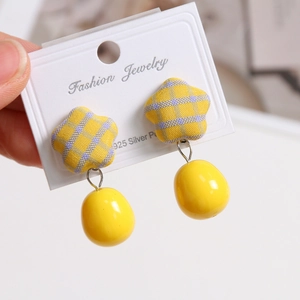 Macro view of S925 silver star earrings with yellow plaid fabric and smooth pendant