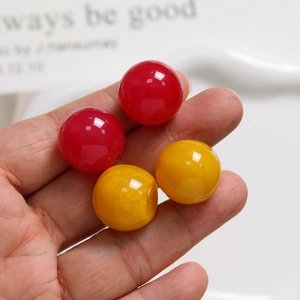 Detailed macro view of 20mm round resin beads in red and yellow on a hand palm