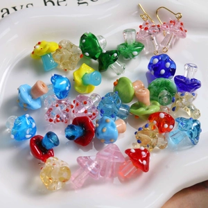 Macro shot of colorful polka dot mushroom glass beads and gold earring hooks on a ceramic tray