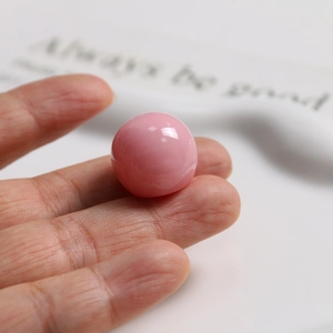 Close-up of a 20mm smooth pink resin bead with ink wash texture for DIY jewelry making
