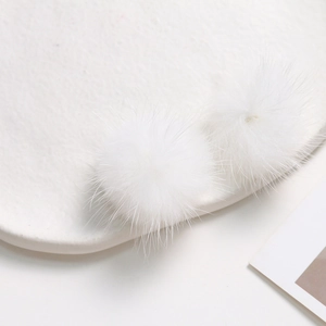 Macro shot of two soft white faux mink fur balls for DIY jewelry and hair accessories