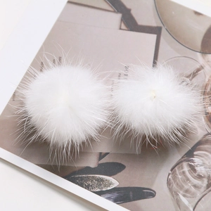 Detailed macro view of pair of white mink fur pom poms for DIY hair accessories