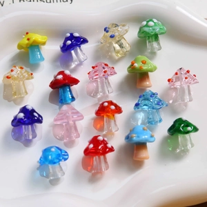 Top view of colorful lampwork glass mushroom beads on a ceramic tray for DIY jewelry