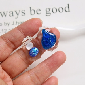 Handheld view of geometric resin charms with blue teardrop sequins for DIY jewelry