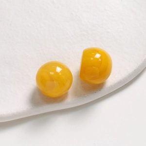 Detailed close-up of 20mm yellow resin round beads with marbled ink texture for DIY jewelry