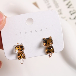 Detail of mini resin leopard print running cat stud earrings on jewelry display card
