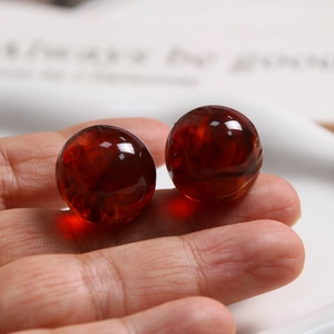 Macro shot of 20mm dark red resin beads with natural cloud texture held in hand