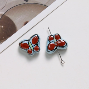 Vue détaillée de perles papillon en céramique peintes à la main pour création de bijoux