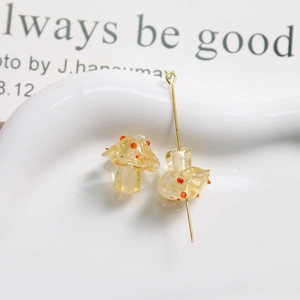 Macro shot of yellow glass mushroom beads with red dots and gold metal pins for DIY jewelry