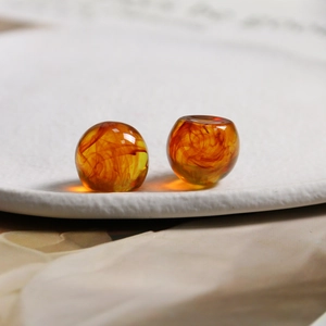 Macro detail of amber resin beads with orange smoke texture on a white ceramic plate