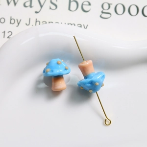 Macro shot of blue glass mushroom beads with polka dots and golden pendant pin detail
