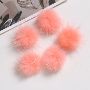Close-up of five soft pink faux fur pompoms for DIY crafts and clothing accessories