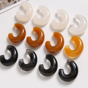 Detail of C-shaped resin jewelry components with ink-wash texture and marble patterns