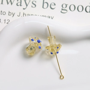 Macro detail of yellow translucent glass mushroom bead with blue dots and gold metal pin