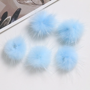 Close-up of five fluffy 3cm sky blue faux mink fur pom poms for DIY crafts and accessories