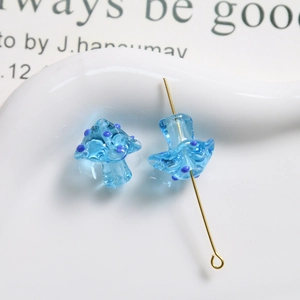 Close-up of translucent light blue glass mushroom beads with purple dots for DIY jewelry