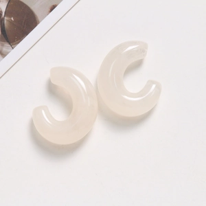 Detailed macro shot of translucent milky white C-shaped resin earrings on a clean backdrop